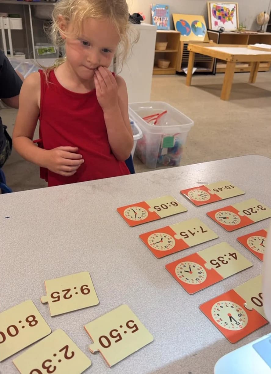A child laying out clock cards, learning to tell time