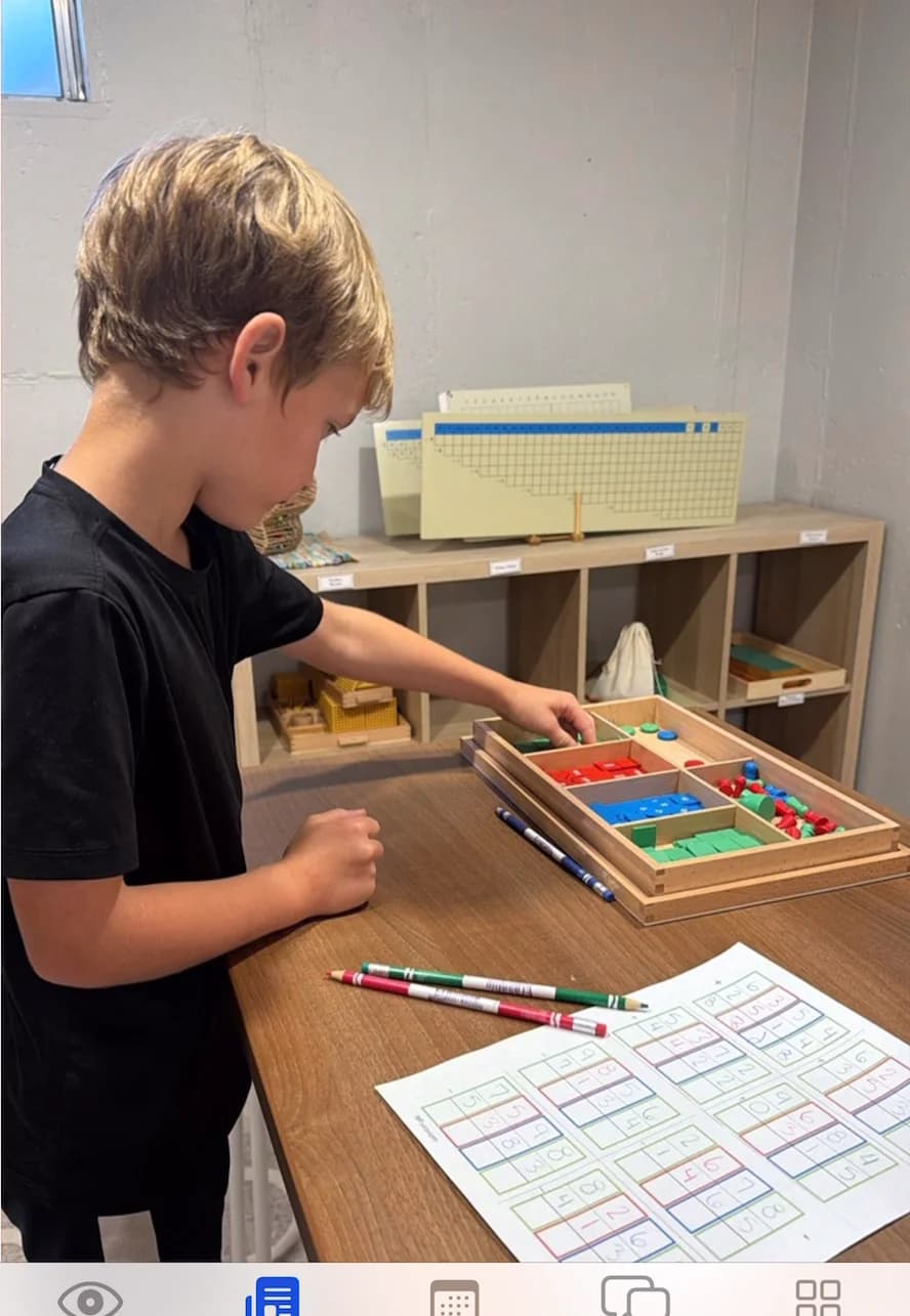 A child working with the stamp game at a wooden table